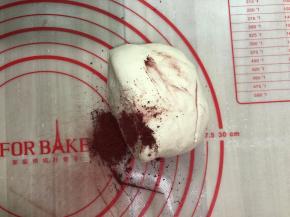 将揉好的面团平均分割成两份，其中一份加入红曲粉继续揉，揉到红曲粉和面团完全混合均匀。剩下的一半放回面包机桶内，防止面团表面变干。