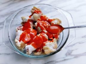 再把调料汁倒进装鸡翅的器具中。