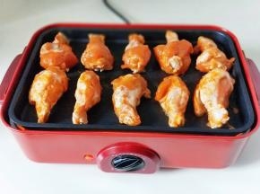 之后把腌制好的鸡翅根摆放在美食锅的烤盘上，再加入半碗水，（水量不要太多）