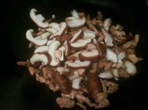 看肉丝变色后，翻炒几下，加香菇丝翻炒出香味