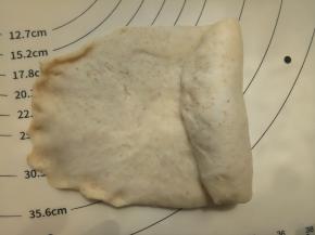 取一份面团擀成牛舌形，然后卷起来。