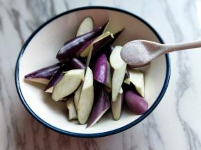 首先把茄子洗干净，再切菱形块，放大口器具中，加入1小勺食用盐，加纯净水，没过茄子为佳，侵泡10分钟这样只需要少量的油就可以把茄子炸软，而且还能去除茄子的涩味，保持它的颜色不氧化。