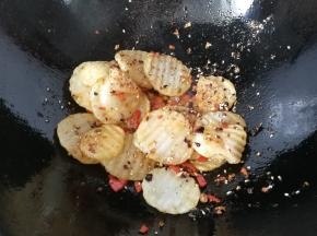 下入炸好的土豆片，调入适量盐、胡椒粉和鸡精翻炒均匀