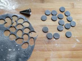 先把黑色面团擀成薄面片，用小号裱花嘴，刻出8对小圆片