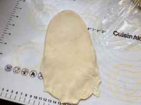 取一个面团，擀成牛舌型，底部搓薄。从上往下卷。周边有气泡用手拍掉。