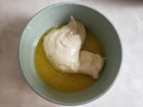 黄油、清水隔热水融化后，舀入一勺蛋黄糊混合均匀。