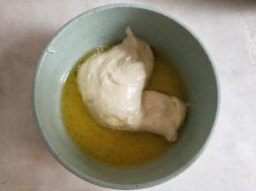 黄油、清水隔热水融化后，舀入一勺蛋黄糊混合均匀。