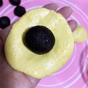 南瓜饼皮压扁，包上豆沙馅，收口成球状。