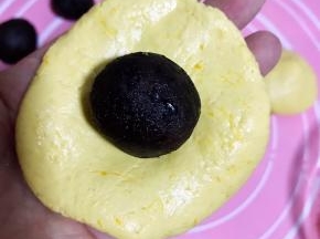 南瓜饼皮压扁，包上豆沙馅，收口成球状。