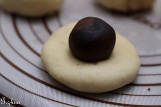 把面团用手按压扁包上豆沙馅，收口朝下。