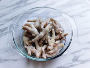 冰过的鸡爪捞出淋干水分，放入玻璃的器具中。