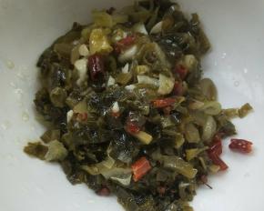 用漏勺捞出酸菜放大碗中。