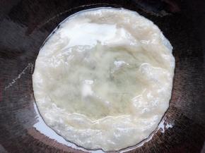 锅里油热放入手抓饼皮煎熟