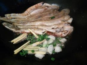泥鱼煎好、用铲子轻轻推一边，下生姜丝，葱末
