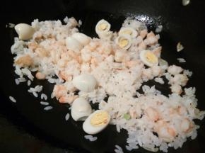 锅里加一点油，下明虾滑炒，明虾可以一整只，也可以切小段来炒，等明虾炒到变颜色，加鹌鹑蛋、米饭一起翻炒