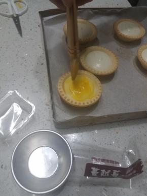 取出凝固好的蛋挞，在表面轻轻的刷上一层蛋液。