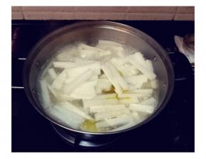 捞起鸡骨，锅里的汤水继续煮沸后，加少许盐，先放入萝卜条，慢火煮至六成熟