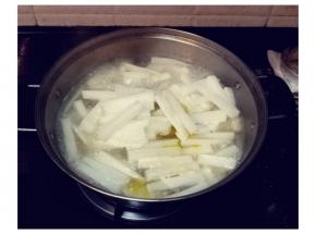 捞起鸡骨，锅里的汤水继续煮沸后，加少许盐，先放入萝卜条，慢火煮至六成熟