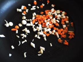 锅内放油烧热，放入胡萝卜丁和蘑菇丁，翻炒半分钟