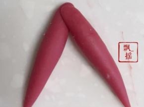 剩下红色面团一分为二，搓成梭型，整成倒V