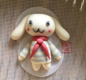 组装，身体顶端抹少许牛奶，粘合红圆圈，倒V置于胸前，搓一颗黄豆大小的红面团作为领结，抹少许牛奶粘合，头部和身体粘合，蓝色面团搓两颗绿豆大小，粘合在头部两侧，黑色面团搓两个比蓝色稍微小点的圆球，抹牛奶粘上去，再搓一丁点白面团粘在黑眼珠上，黑色面团搓细做出嘴巴，粘上腮红。