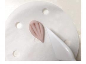 取粉、紫、黄面团各一克，搓水滴压扁用工具压出三道痕迹