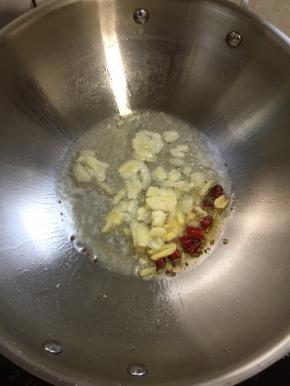 锅烧热倒入适量的油，放入蒜瓣，生姜，干辣椒爆香。