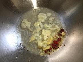 锅烧热倒入适量的油，放入蒜瓣，生姜，干辣椒爆香。