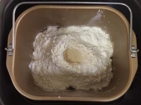 除黄油以外的面包材料都放入面包机内（先液体后粉类的顺序），在面粉中间挖个洞，把酵母粉倒入，启动和面程序。