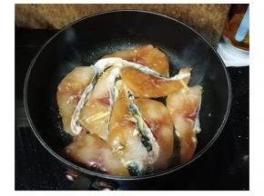 蒜、姜片爆香后，放入腌制好的鱼腩，慢火将两面煎至肉变白色
