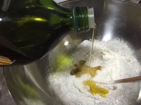 倒入20克橄榄油，清水、白砂糖和食盐（这里需要注意酵母粉与食盐要对角放置），用筷子将面粉搅拌成絮状再揉成光滑面团