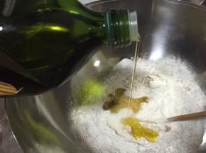 倒入20克橄榄油，清水、白砂糖和食盐（这里需要注意酵母粉与食盐要对角放置），用筷子将面粉搅拌成絮状再揉成光滑面团