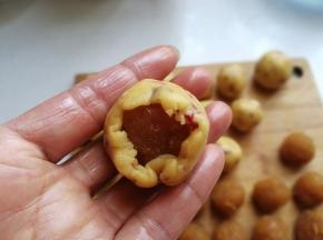再取一份凤梨内馅放入面皮中，用虎口向上收拢捏紧，然后像包月饼一样把面皮向上推挤包好滚圆