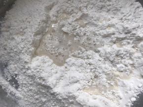 慢慢倒入饼皮面粉中，搅拌成絮状，再揉成光滑面团