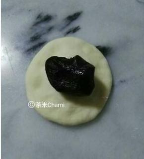 面团平均分成40克左右的剂子，包入豆沙馅，收好口，整成圆包。 