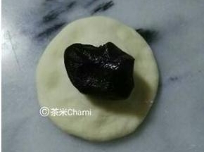 面团平均分成40克左右的剂子，包入豆沙馅，收好口，整成圆包。