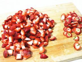 将草莓头切掉一部分，剩下的切成小块。