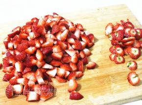 将草莓头切掉一部分，剩下的切成小块。