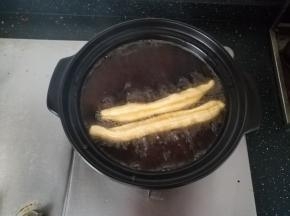 油锅烧热。把油条胚，捏住两头，拉伸至1倍，下油锅。