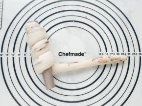 将长条面团的一头贴住摞管的一端，然后顺势绕圈卷起。