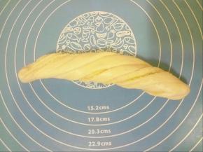 抓起面团两头，慢慢抻长一些，两条长边同时向相反方向卷起，卷成一个长条圆筒形，尽量让切割口朝外，像扭麻花一样扭转两至三圈。