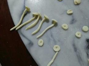 长条要再搓一搓，成圆柱体。长条要长短不不一，才好看。小圆，中间戳一下洞，沾水贴上长条，金针菇就出来了。