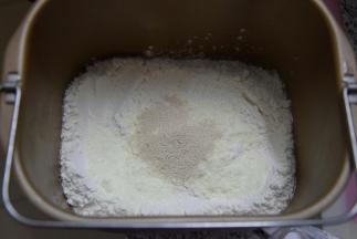 将除黄油外的其他食材全部倒入面包桶中，酵母避免与水和盐接触，启动面包机揉面功能