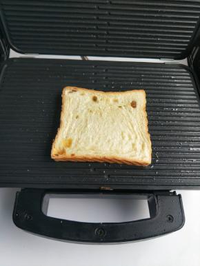 然后换上条型模具，加热刷上一层油，放入一片吐司。