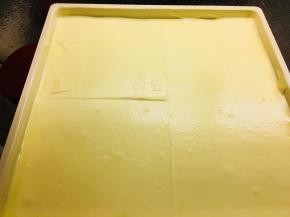 取出冷藏中的烤盘，将搅拌好的蛋糊倒进去。抹平，震荡烤盘震出气泡。