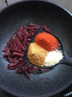 放入两勺辣椒粉，三勺小丑娃孜然粉，一勺鸡精翻炒均匀。