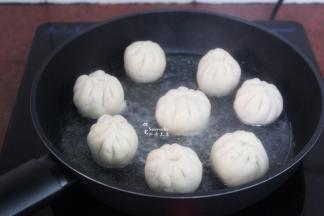 热锅，倒入一点油，放入包子胚，小火煎微黄，加入适量的水；