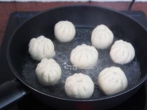 热锅，倒入一点油，放入包子胚，小火煎微黄，加入适量的水；