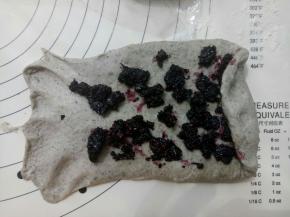 面团擀成牛舌形铺上桑葚酱卷起来。盖保鲜膜松弛15分钟。