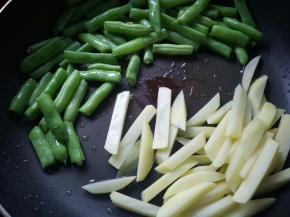 炒至四季豆断生，皮皱起。放入土豆条炒至断生。